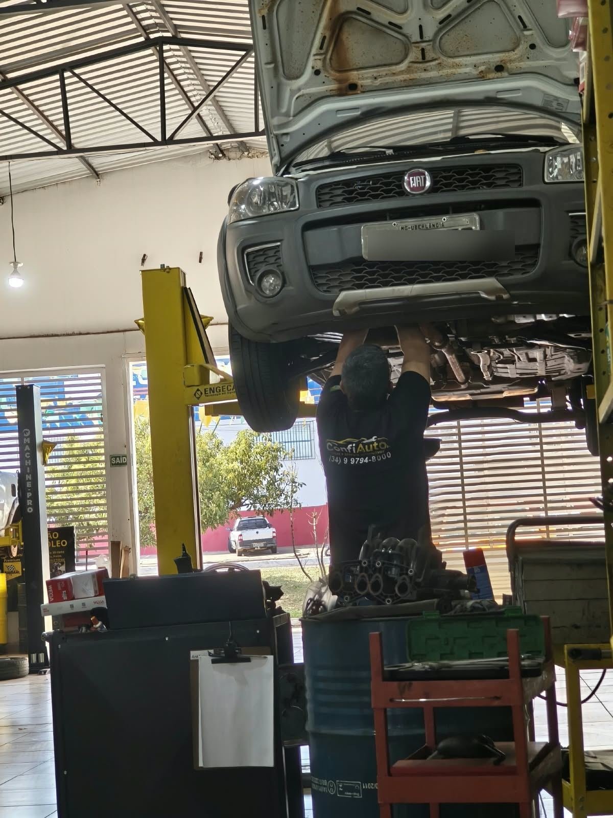 Mecânico da Confiauto revisando a parte inferior de um veículo no elevador